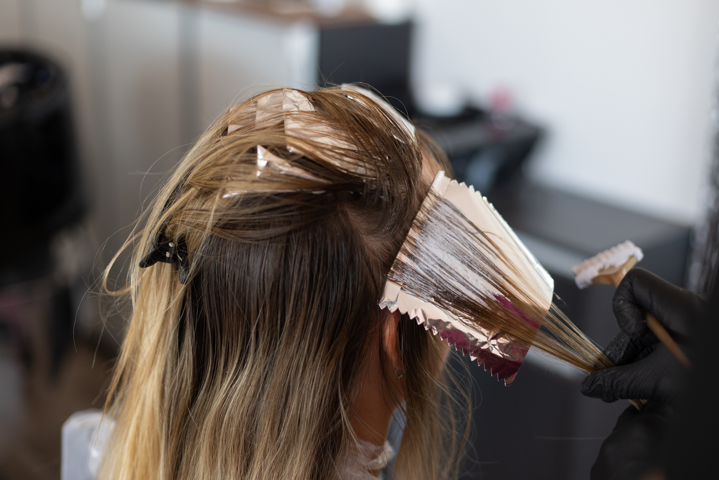 Colourist putting hair dye on a lock of hair with foil.